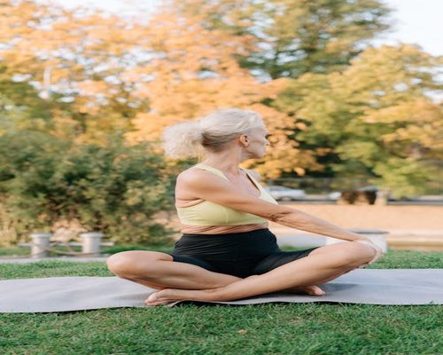 senior woman stretching in a park with sunlight